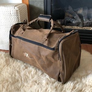 TJX REWARDS brown large duffel bag with side pockets.